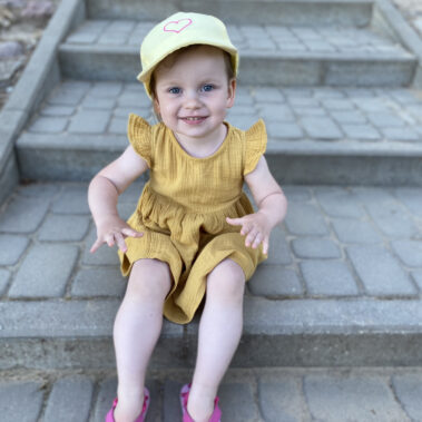 mała dziewczynka siedząca na schodach w żółtej muślinowej sukience